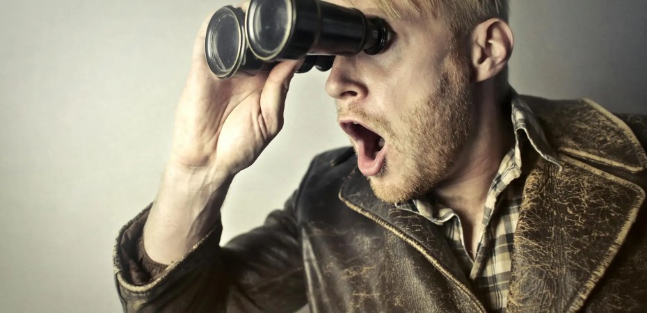 man in brown leather jacket using binoculars